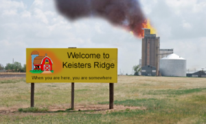 Welcome to Keisters Ridge - When you are here you are somewhere sign with burning grain elevator