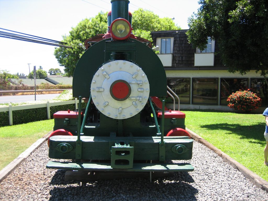 A narrow-gauge steam train engine on display on Maui